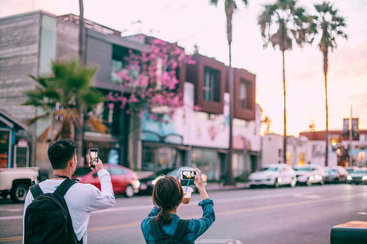 unrecognizable-tourists-taking-pictures-on-smartphone-of-tropical-city-street-4947851